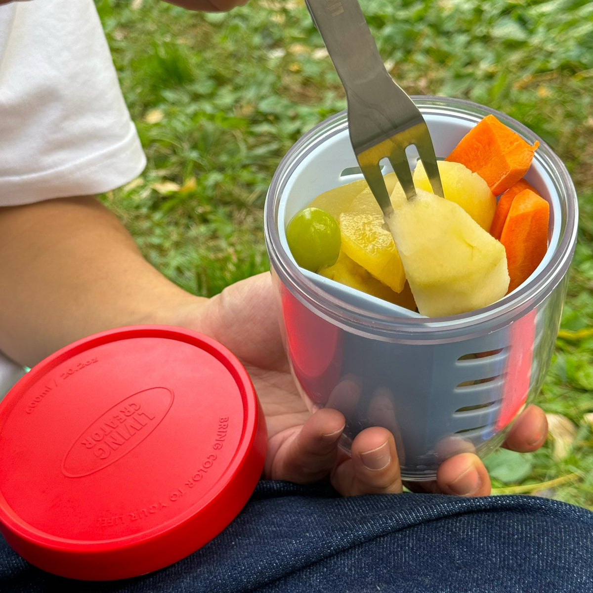 Eating fruit from a KEEPER POT with the included fork at a picnic