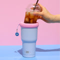 Pastel blue KEEPER TUM with an iced coffee, held in one hand