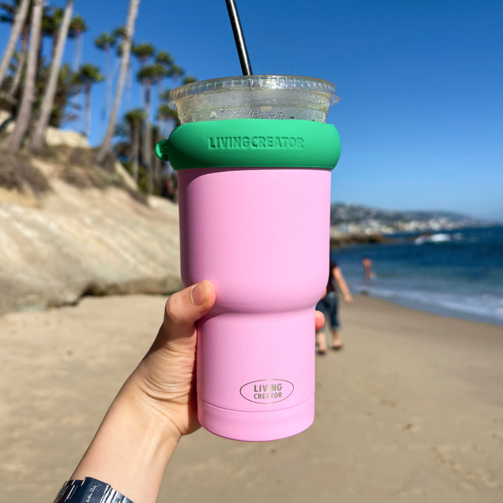 Pink KEEPER TUM Mini with an iced drink at the beach